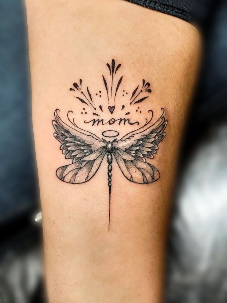 a woman's leg with a tattoo on it that reads mom and features a dragonfly