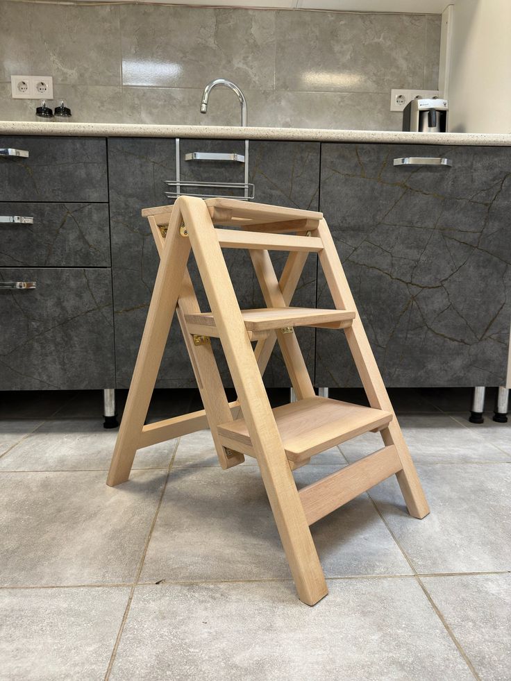 a wooden step stool sitting on top of a kitchen floor