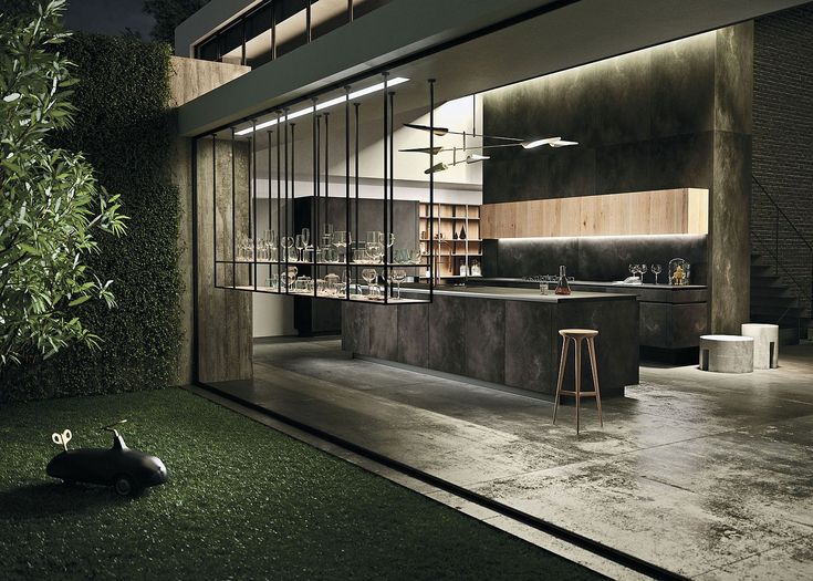 an outdoor kitchen and living room are lit up at night with green grass on the ground