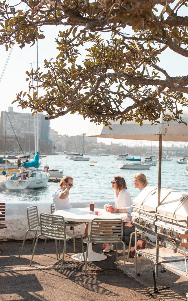 people sitting at an outdoor table near the water