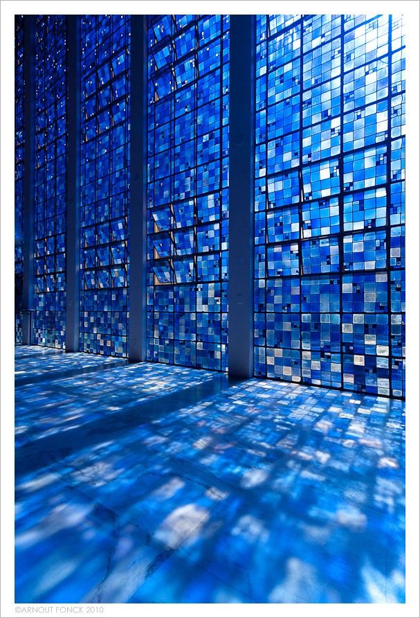 a room with blue glass walls and floor tiles on the wall, in front of a large window