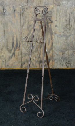 a metal easel stands against a wooden wall with an iron frame and two hooks on each side