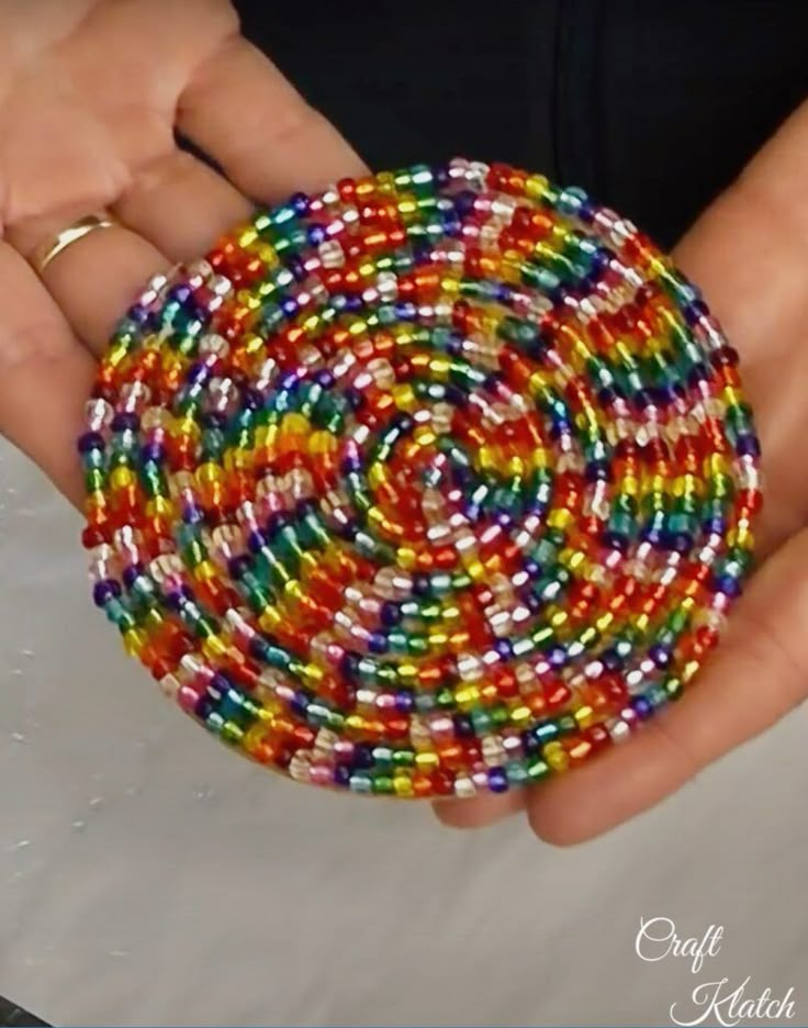 a person holding a colorful beaded object in their hands