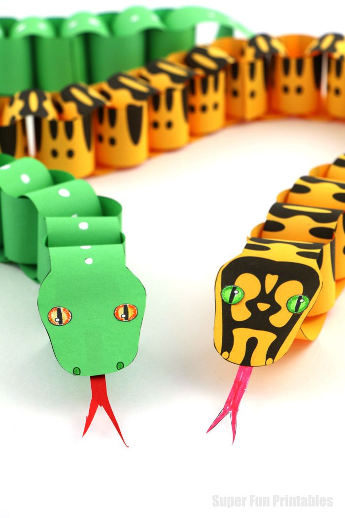 an origami snake is next to some colorful paper chains on a white surface