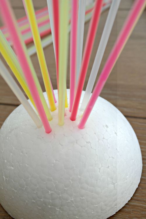 several colored straws sticking out of a white vase