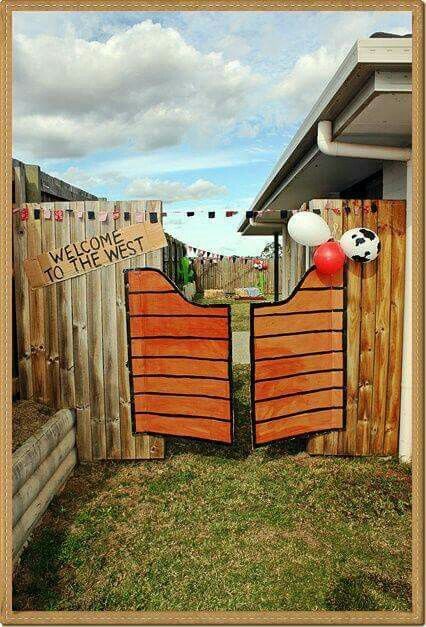 a wooden gate with balloons attached to it in front of a fence that says welcome to the west