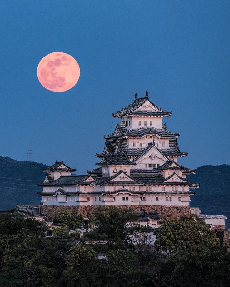 the moon is setting over an old castle