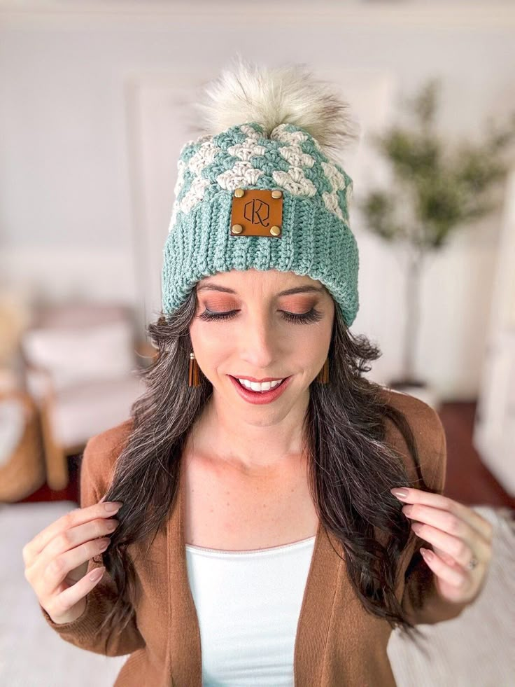 a woman wearing a green hat with white fur pom