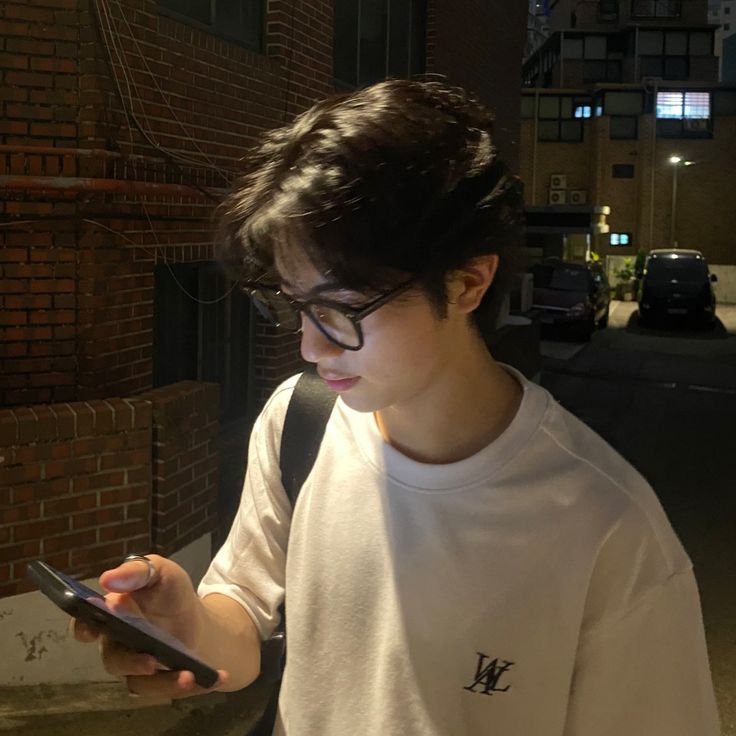 a young man wearing glasses looking at his cell phone