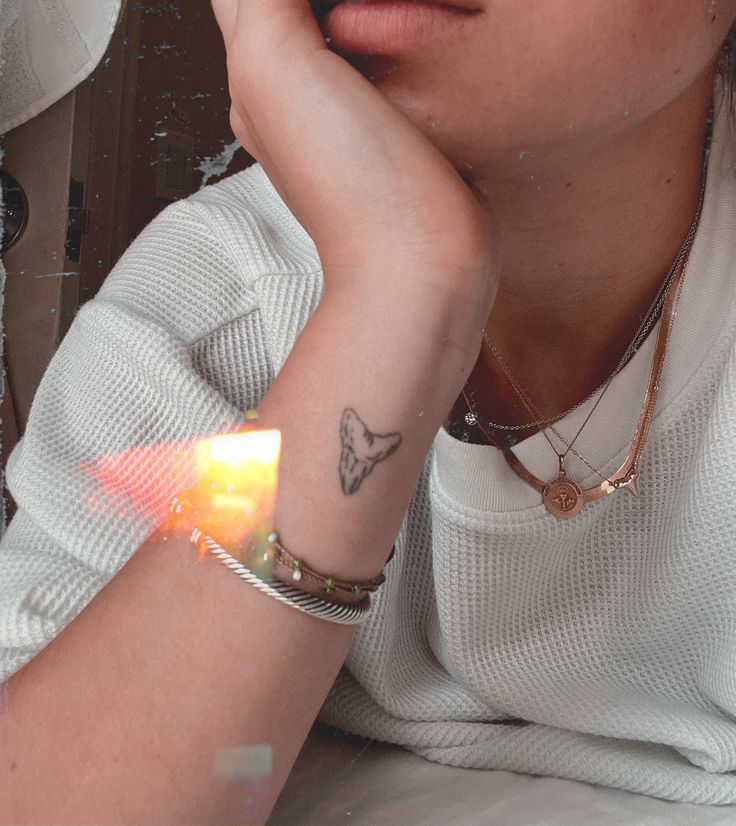 a woman with a butterfly tattoo on her arm holding a lit candle in front of her face