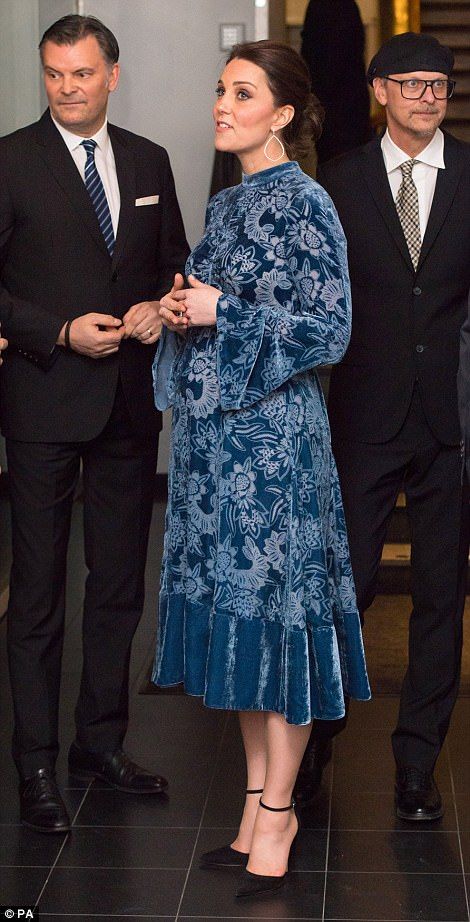 a woman in a blue dress standing next to two men