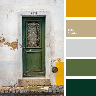 a green door on the side of a white building with yellow trim and brick flooring