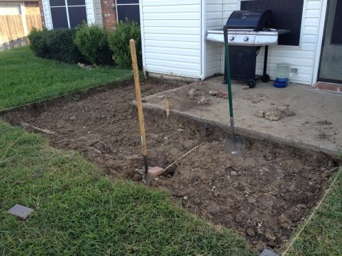 a small backyard with a grill and some plants in the ground next to an open door