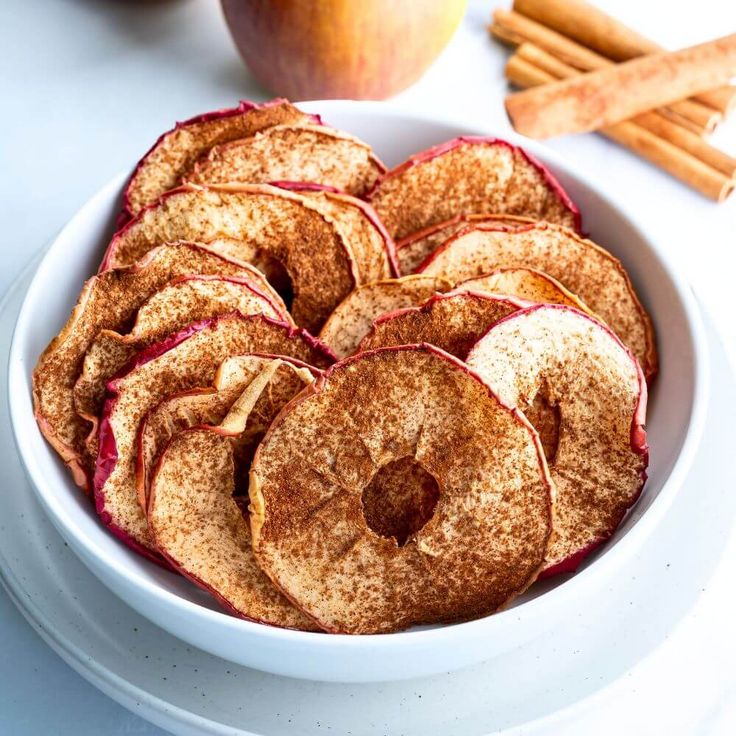 a white bowl filled with sliced apples and cinnamon sticks