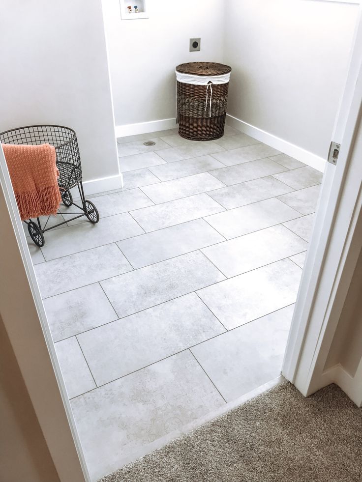 a bathroom with white walls and tile flooring next to a basket on the door