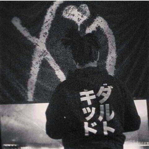 a man standing in front of a graffiti covered wall with writing on it's back