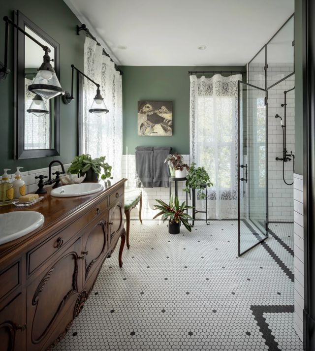 a large bathroom with green walls and white tile flooring, along with two sinks