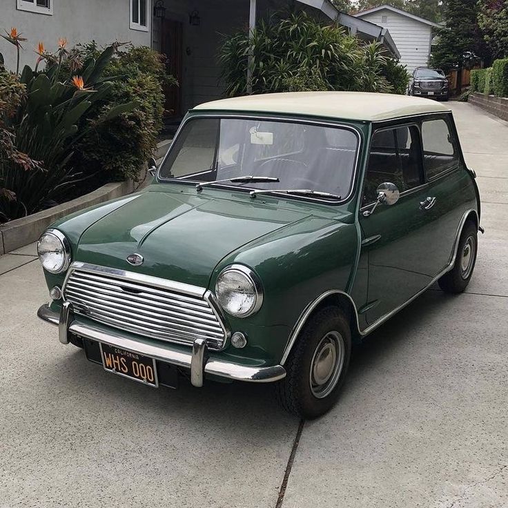 an old green car parked in front of a house