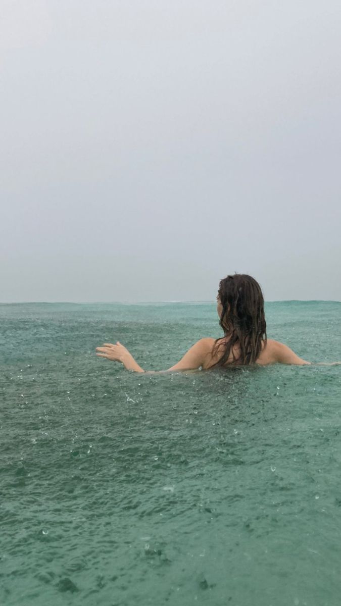 a woman floating in the ocean with her arms outstretched