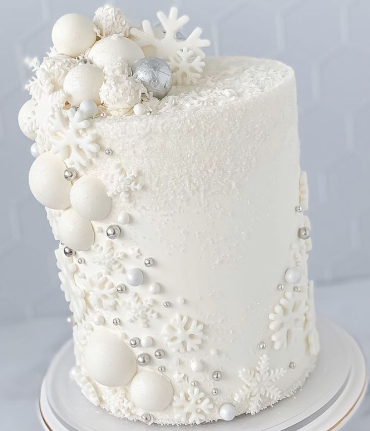 a white frosted cake with snowflakes and ornaments on the top is sitting on a plate