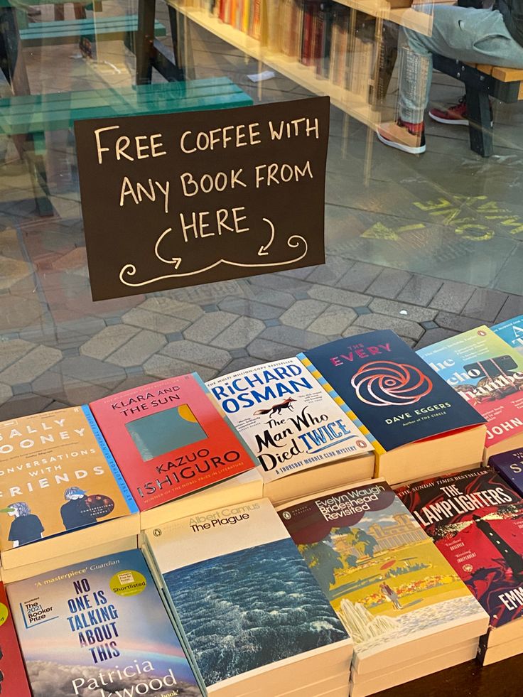 there are many books on display in the store window and one has a sign that says free coffee with any book from here