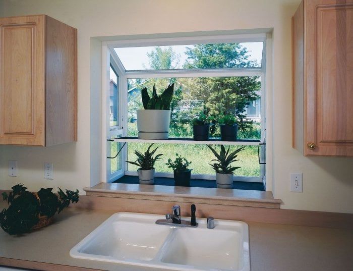 a kitchen sink sitting under a window next to wooden cabinets