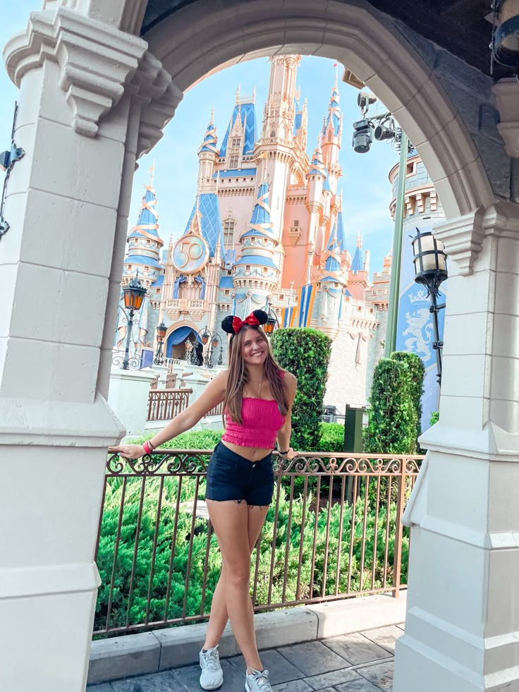 a woman standing in front of a castle with her hand on her hip and looking at the camera