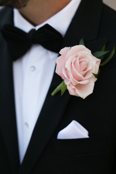 a man in a tuxedo with a pink rose boutonniere on his lapel