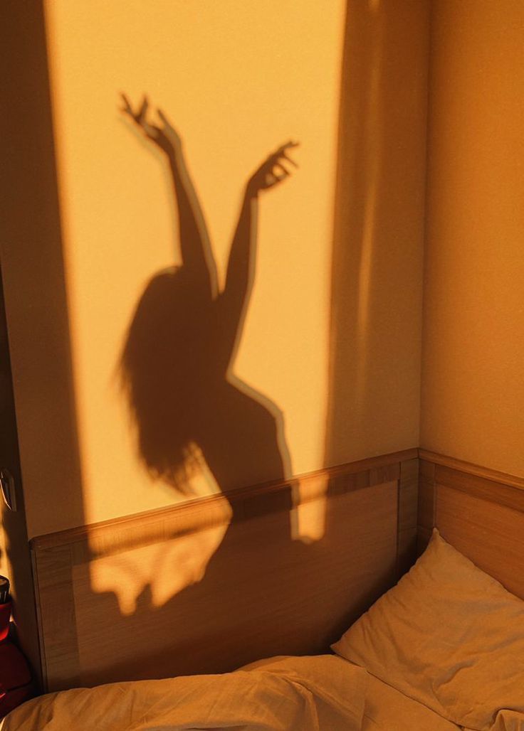 the shadow of a woman dancing on a bed