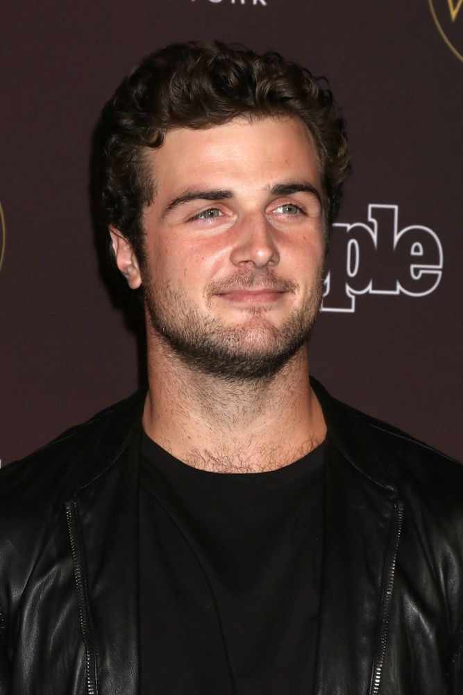 a man in black shirt and leather jacket posing for the camera with his eyes closed