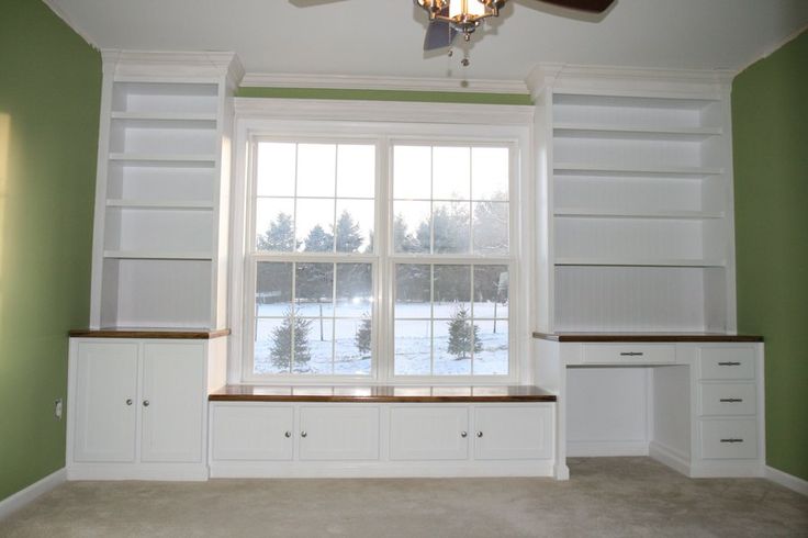 an empty living room with green walls and white built - in shelvings on the wall