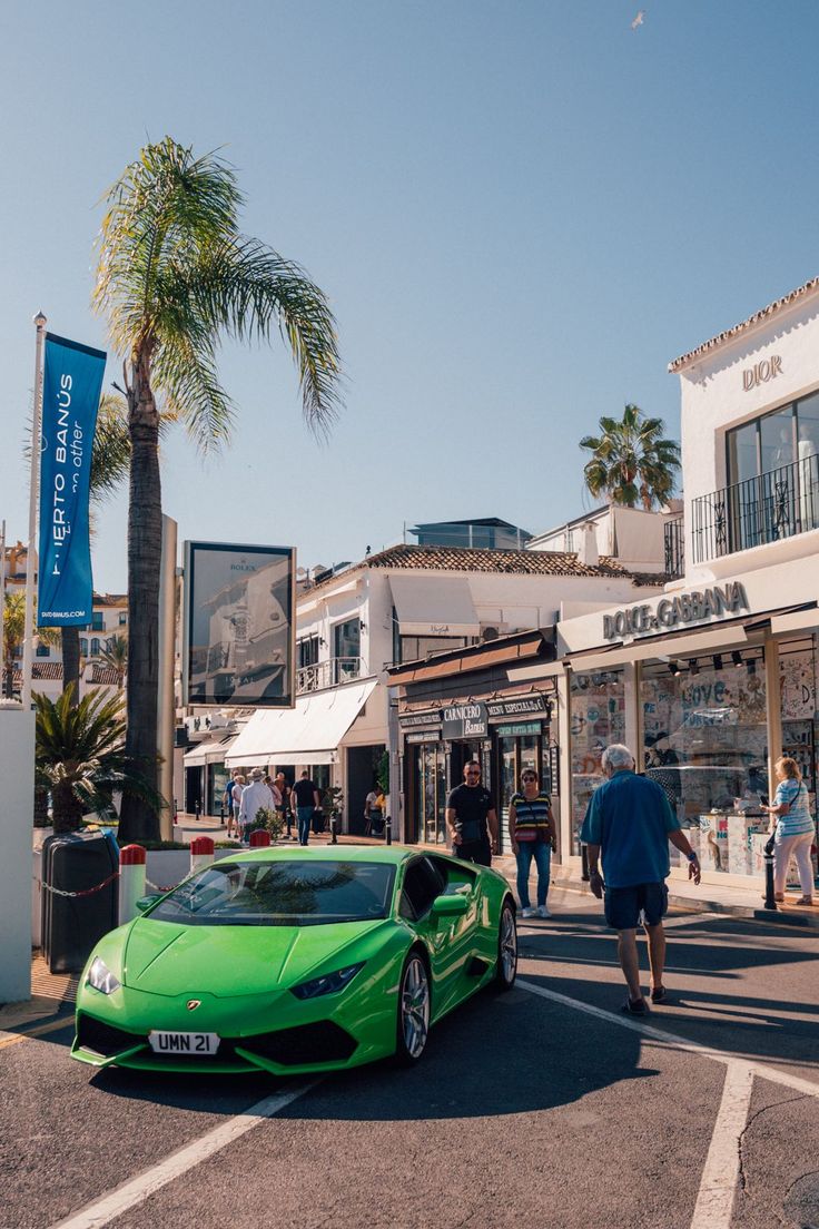 a green sports car parked in front of a store on the side of a road