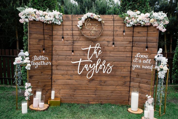 a wooden wall decorated with flowers and candles for an outdoor wedding ceremony in the backyard