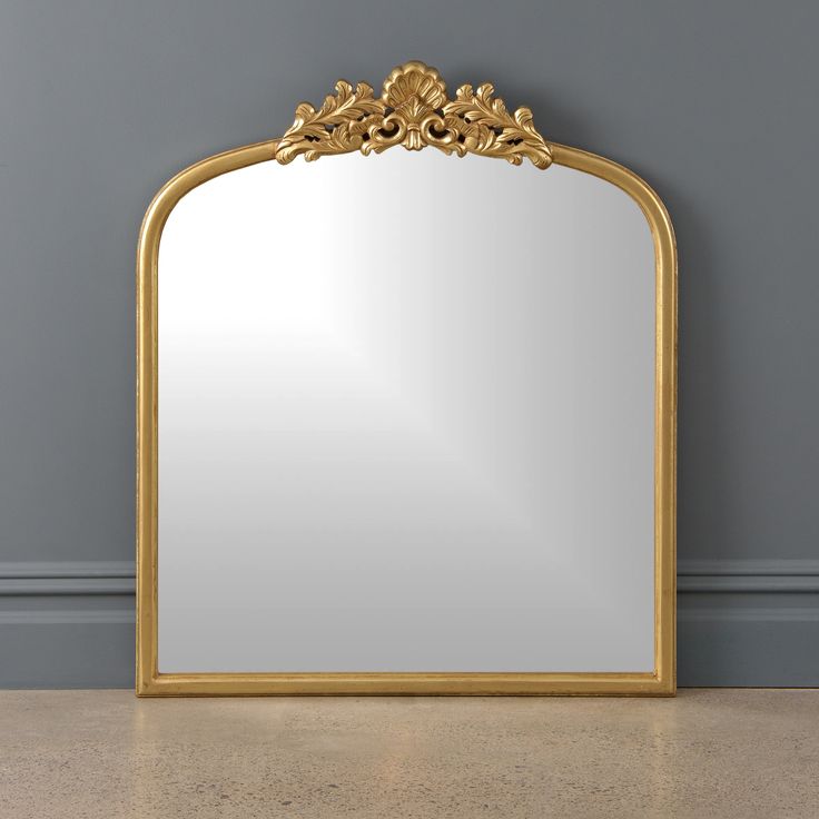 a mirror sitting on top of a floor next to a wall with a gold frame