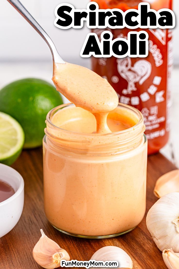 a spoon full of homemade sricha aioi with garlic and limes in the background