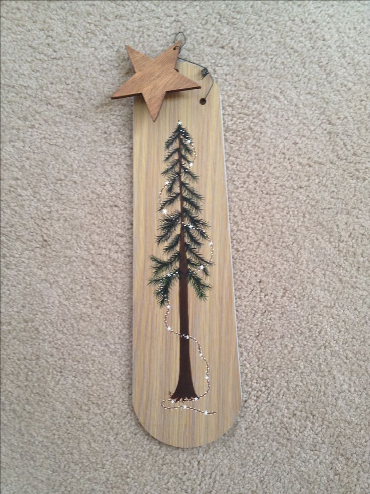 a wooden cross with a tree painted on it and a star hanging from the side