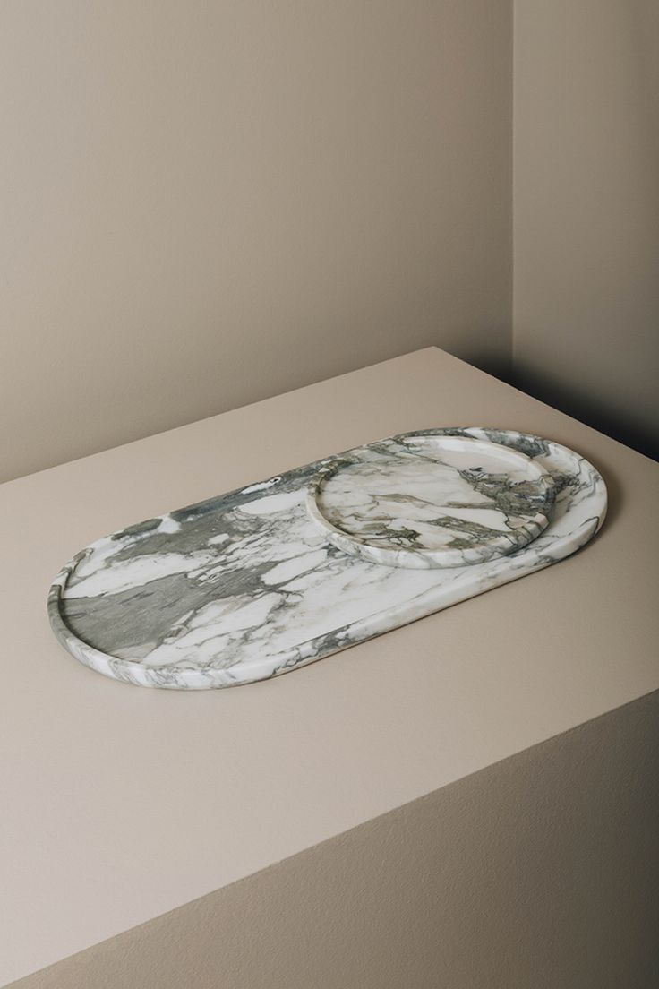 a white marble tray sitting on top of a counter next to a beige wall and floor