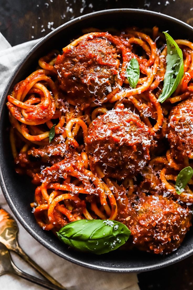 meatballs and spaghetti in a skillet with basil leaves on the side, ready to be eaten