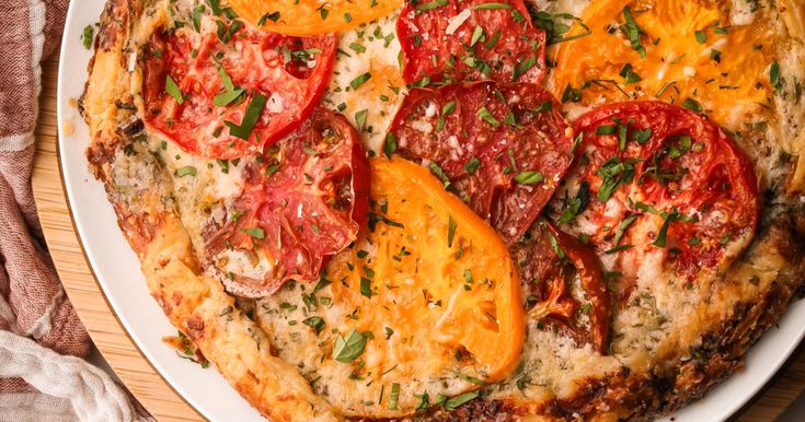 a close up of a pizza on a plate with cheese and tomatoes in the middle