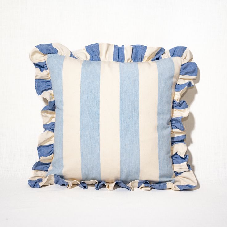 a blue and white striped pillow with ruffles on the bottom, against a white background