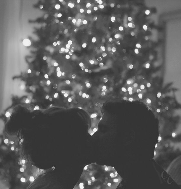 two people kissing in front of a christmas tree with the words, i love you