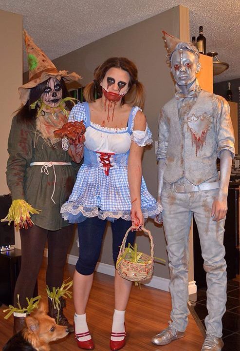 three people dressed up in costumes standing next to each other with a dog on the floor