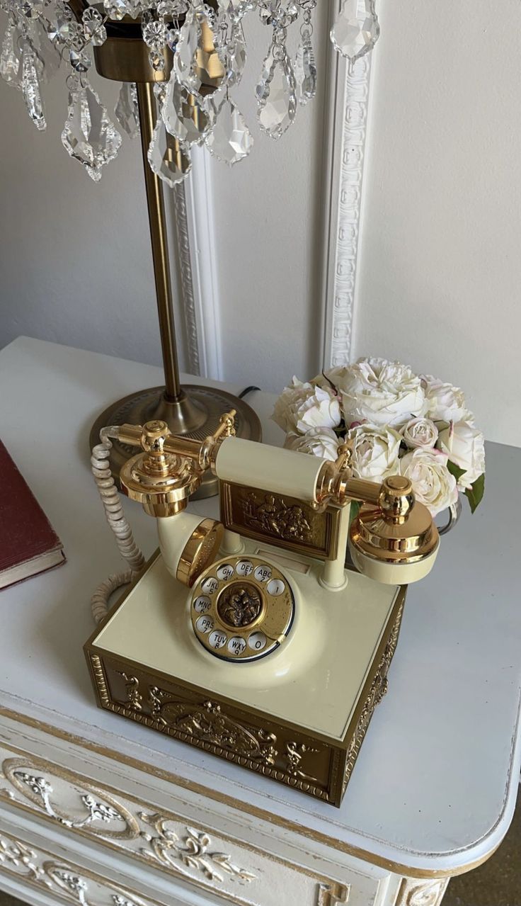 an old fashioned phone sitting on top of a table next to a chandelier