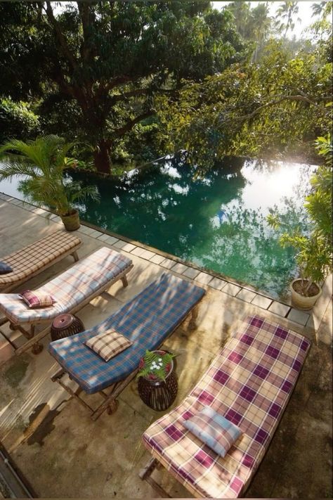 an outdoor patio with chaise lounges next to a pool in the middle of trees