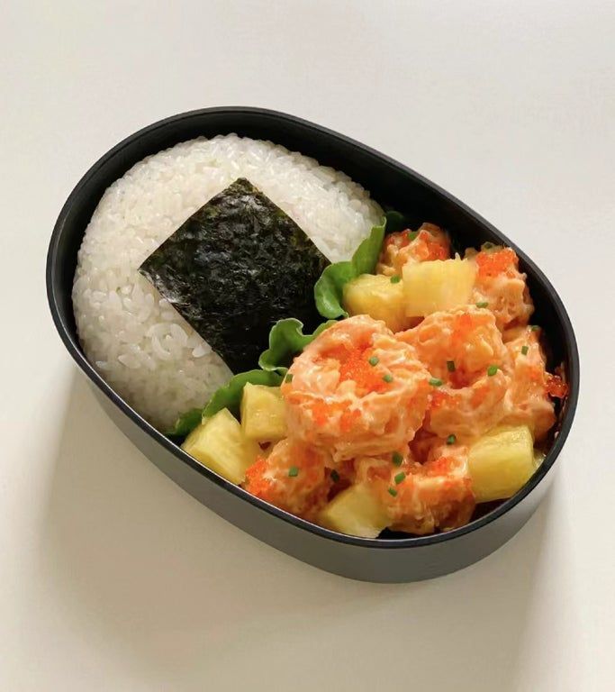 a black bowl filled with rice and veggies on top of a white table