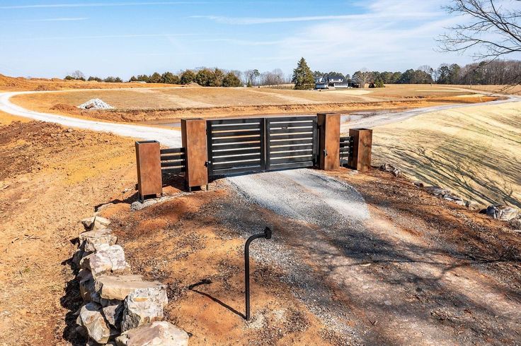 an open gate on the side of a dirt road