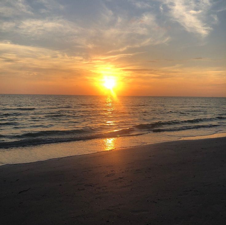 the sun is setting over the water at the beach