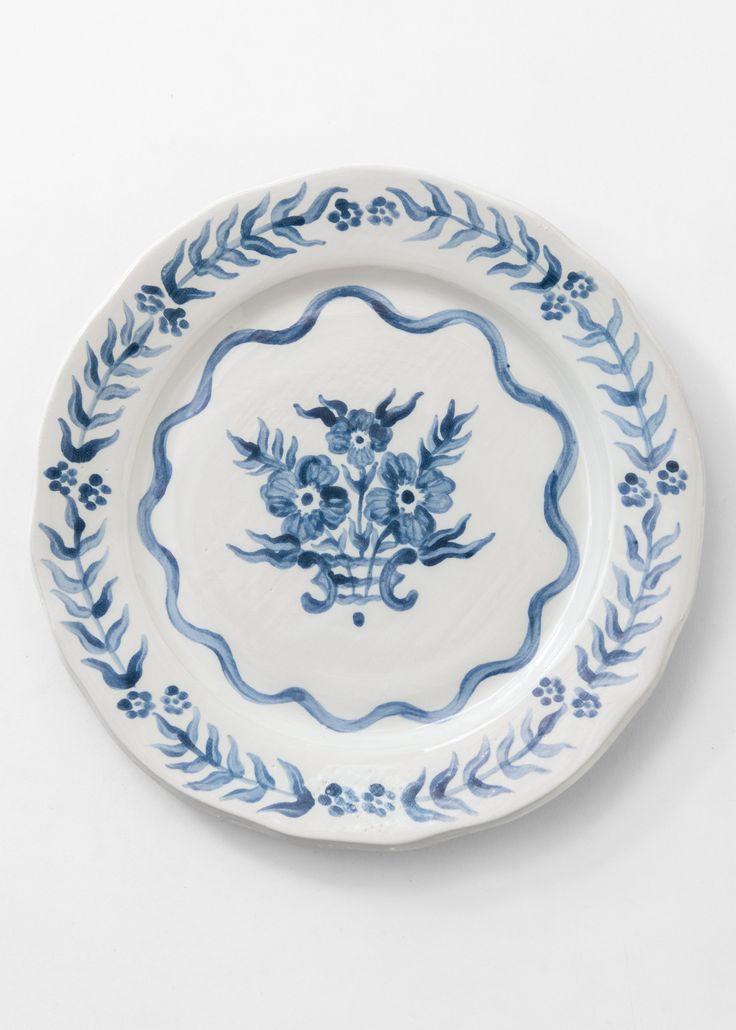 a blue and white plate with floral designs on the rim, against a white background