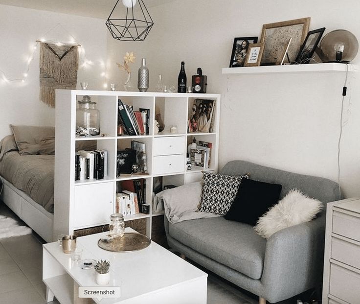 a living room filled with furniture next to a white table and bookshelf on top of a hard wood floor