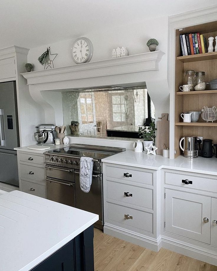 a kitchen with white cabinets and stainless steel stove top oven next to an open book shelf